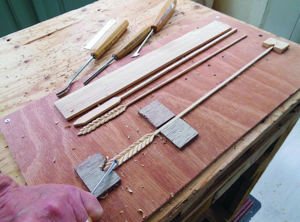 Woodworker carving leaf patterns on wooden strips