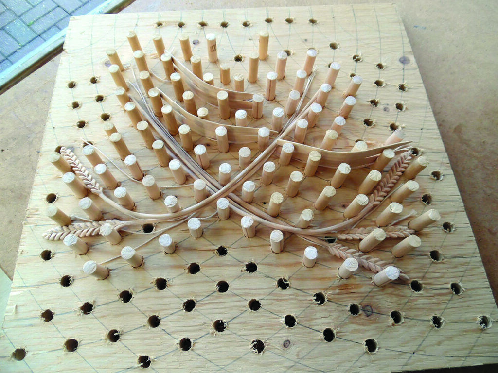 Wooden peg board showing an intricate cord weaving pattern