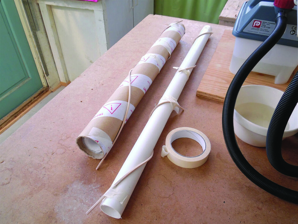 Wrapped tube and white plastic pipe on workshop bench