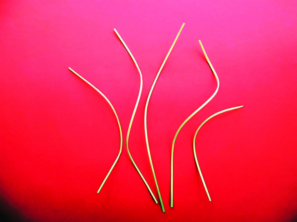 Six curved yellow pasta strands on bright pink background
