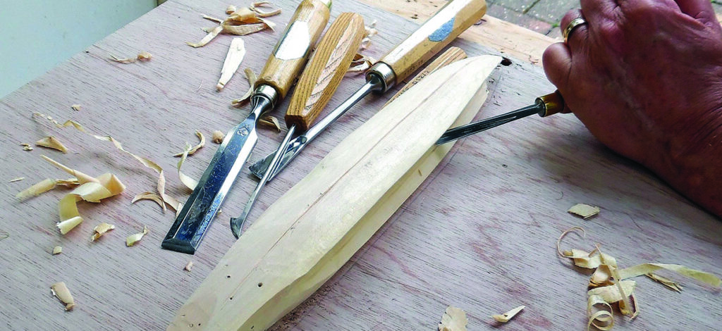 Craftsperson carving a wooden object with a chisel