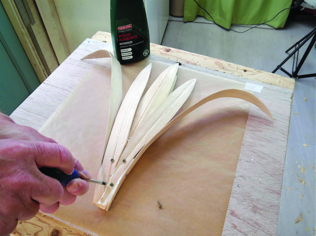 Craftsperson assembling curved wooden strips on a workbench