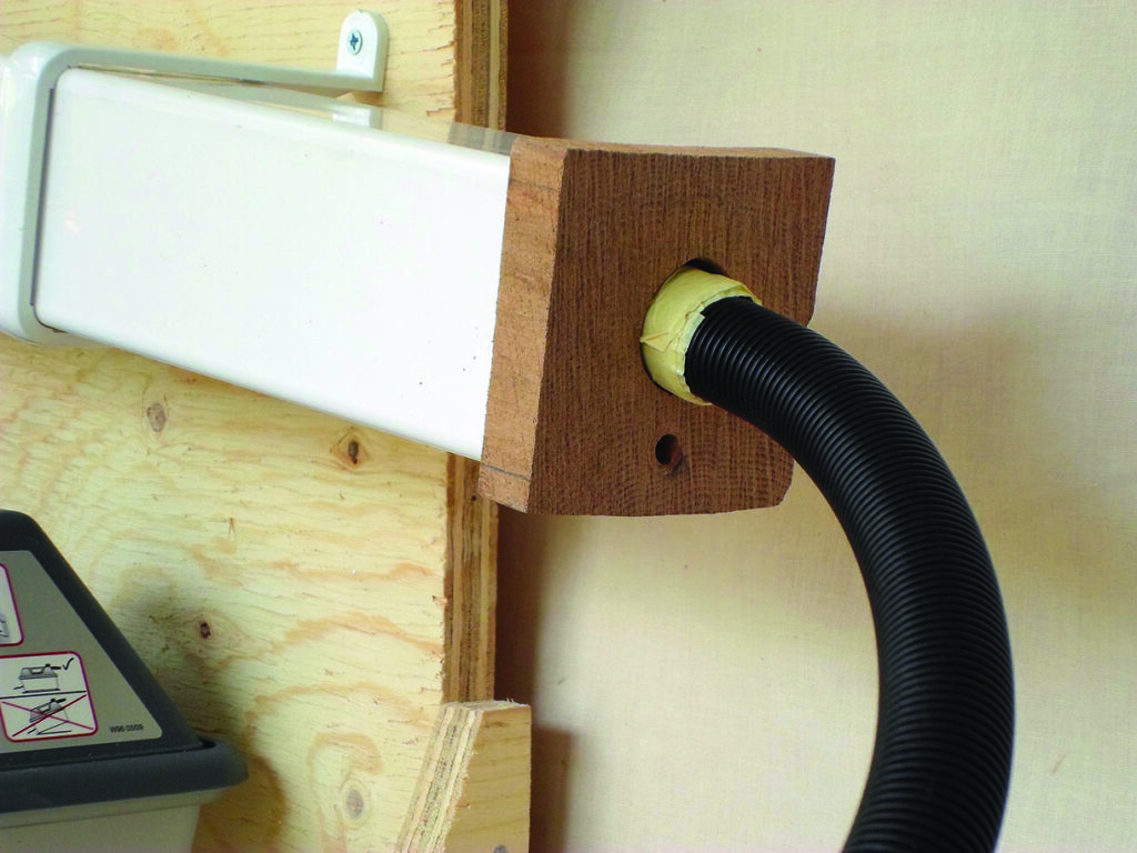 Black hose connected to wooden dust-extraction fitting