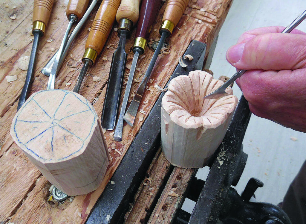 Woodcarver chiselling a flower pattern into a wooden block