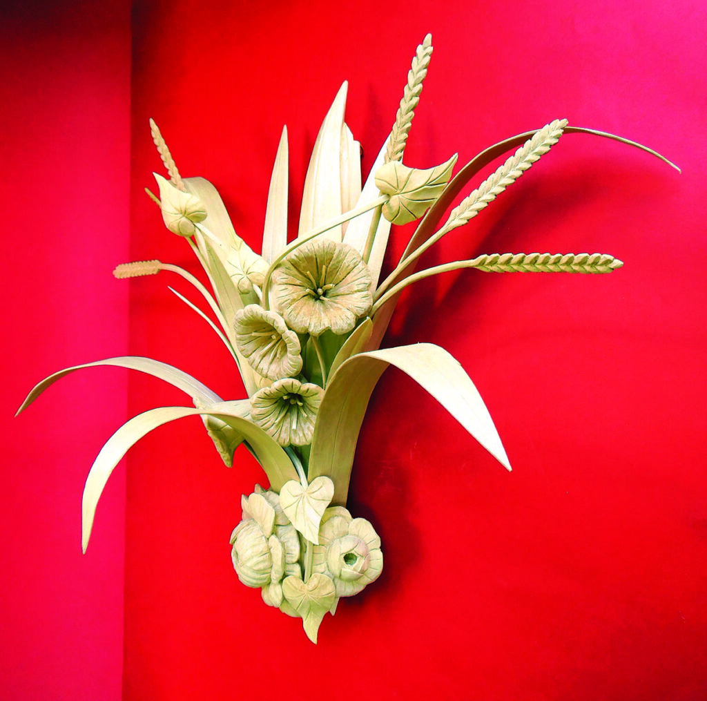 Intricate vegetable and wheat carving on red background