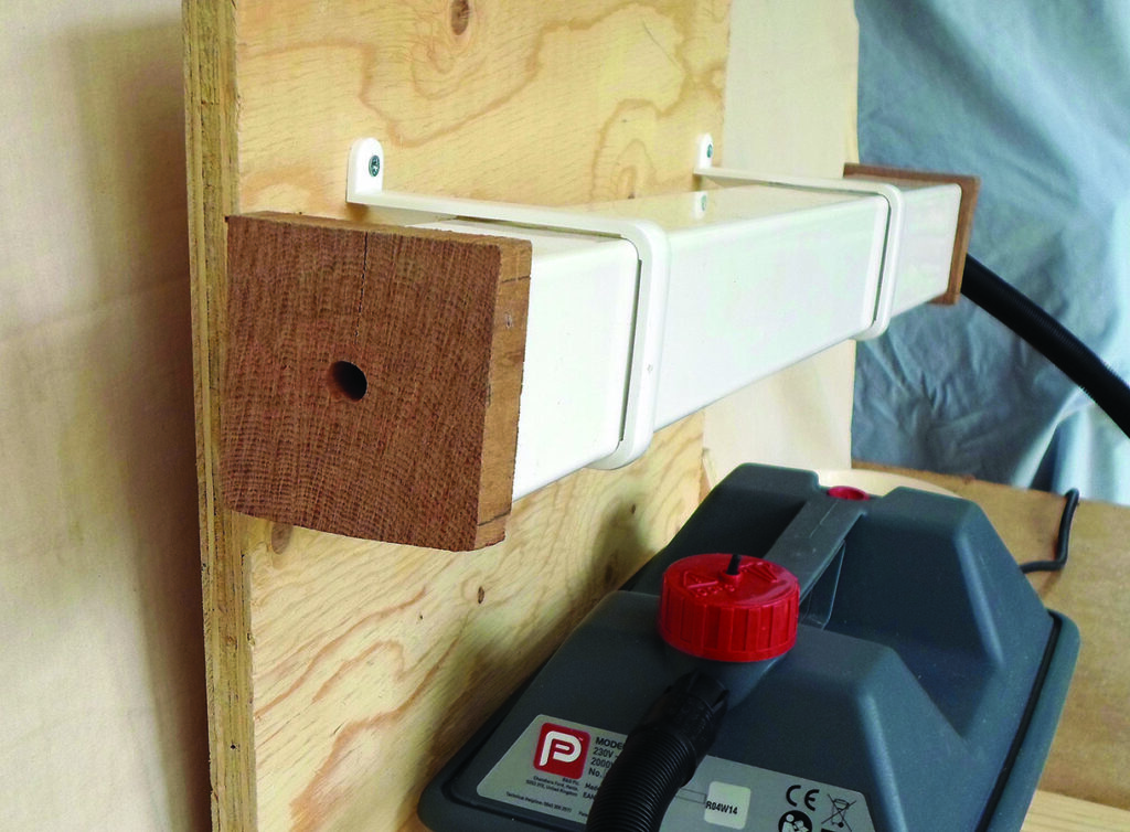 White extraction duct mounted on a plywood workshop panel