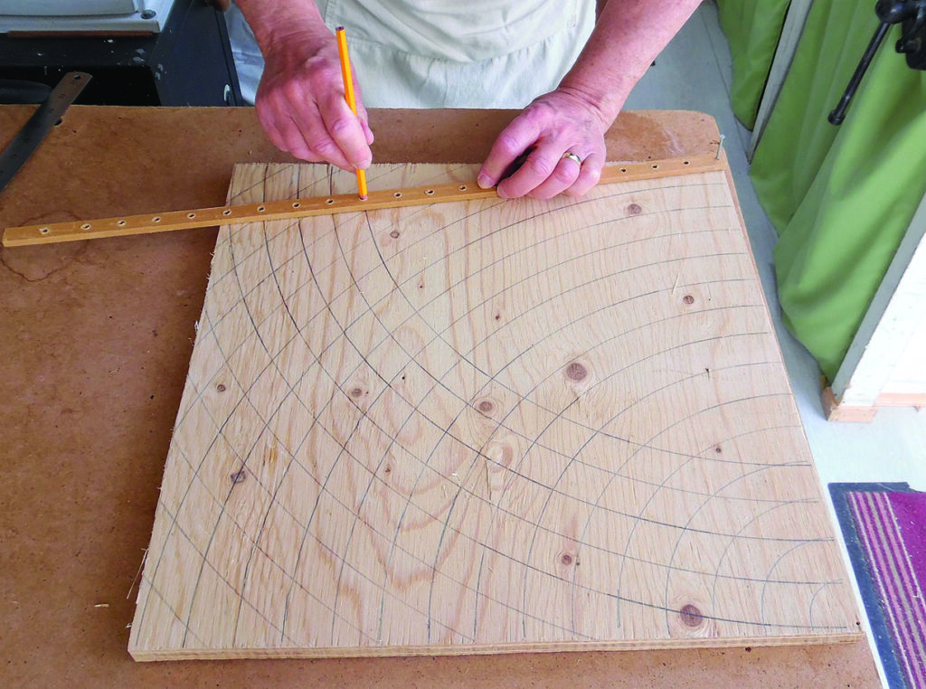Person drawing curved lines on a wooden board