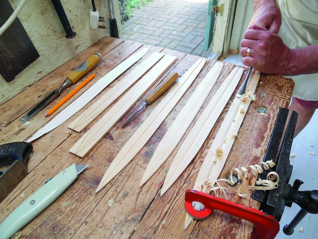 Craftsperson shaping wooden strips on a workbench