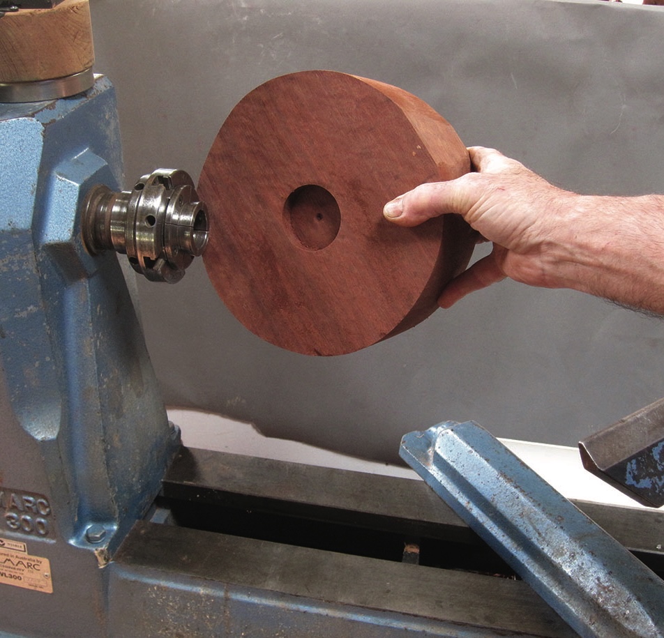 Hand holding wooden block on a lathe