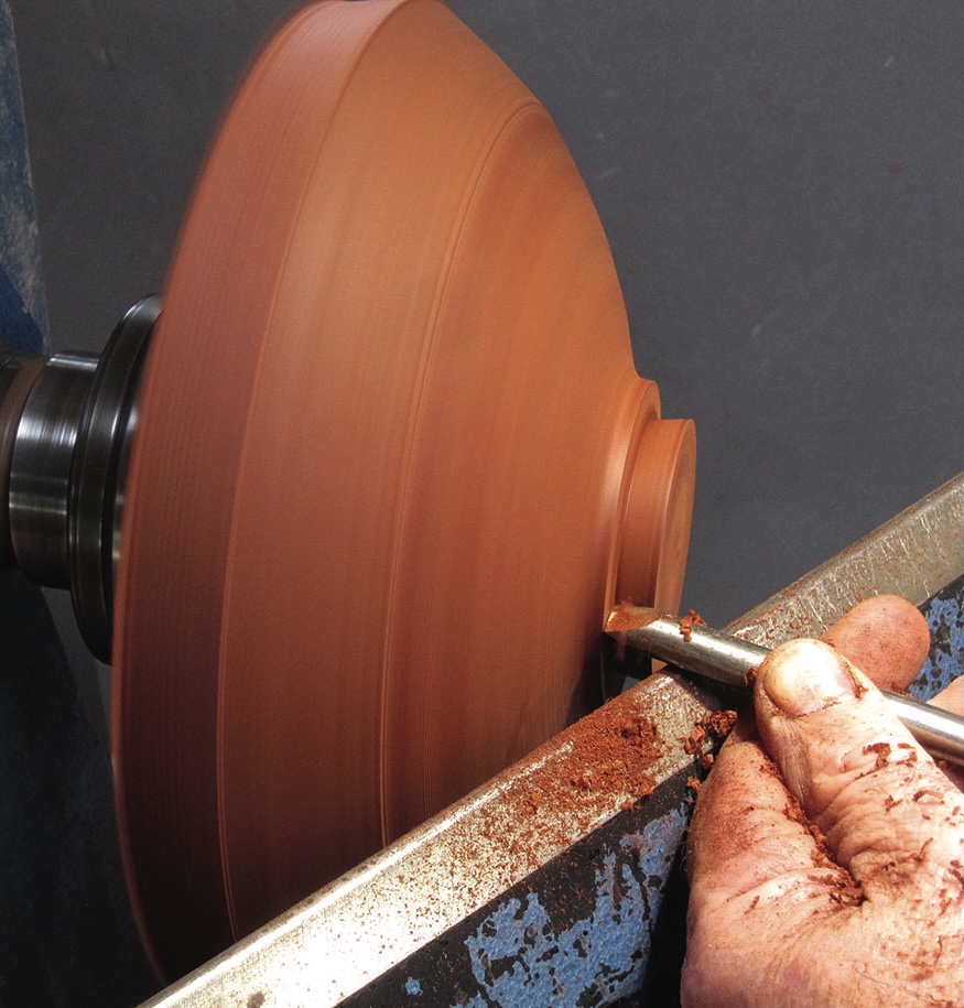 Woodturning on a lathe with carving tool.