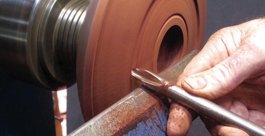 Woodturning on lathe with hand tool.