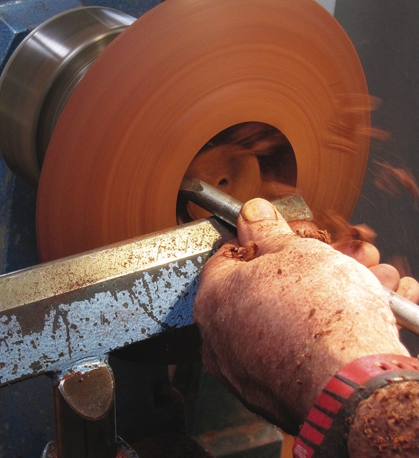 Craftsman using lathe to shape wood bowl