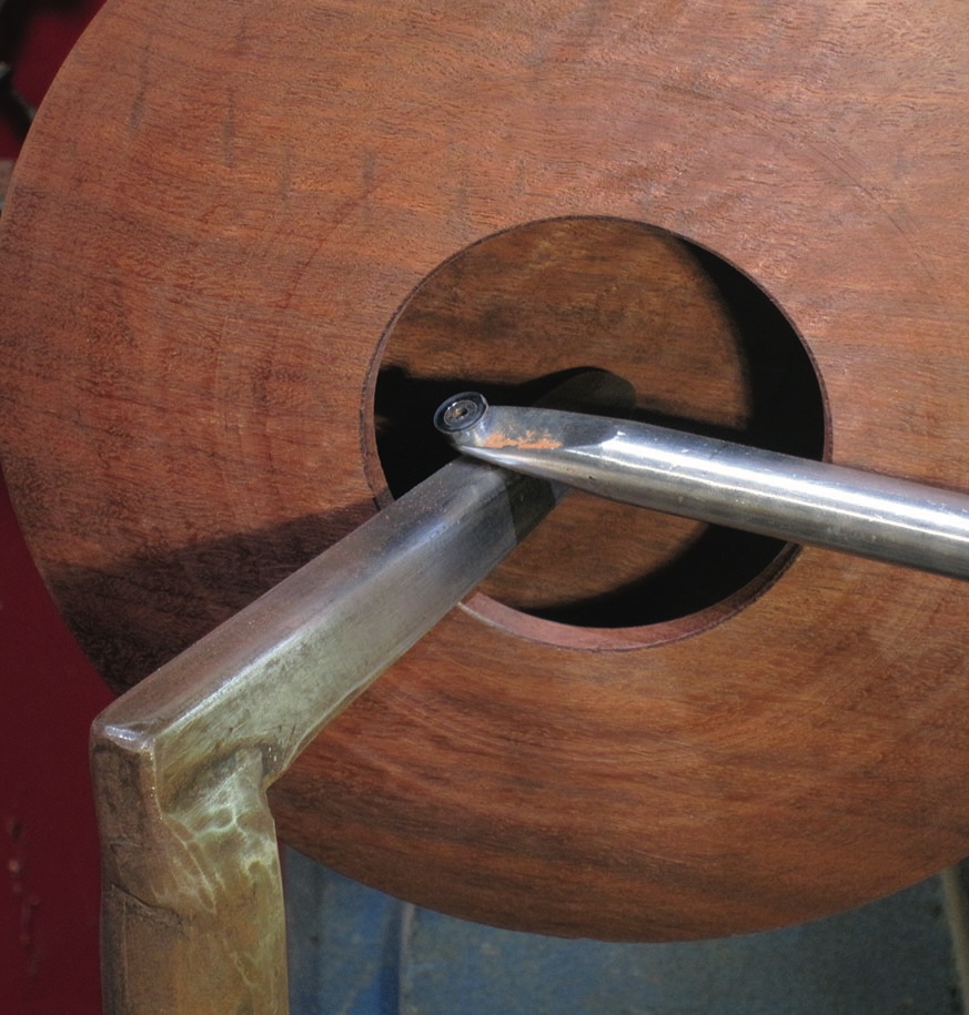 Woodturning tool carving wooden bowl interior.