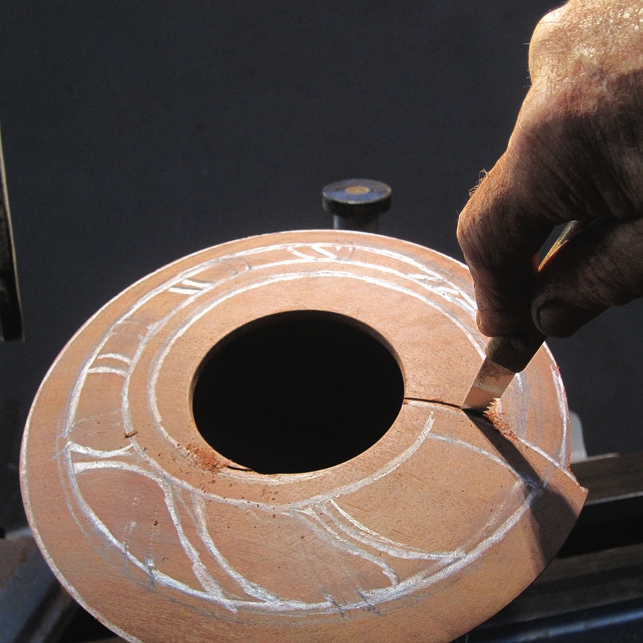 Hand carving intricate design on pottery wheel
