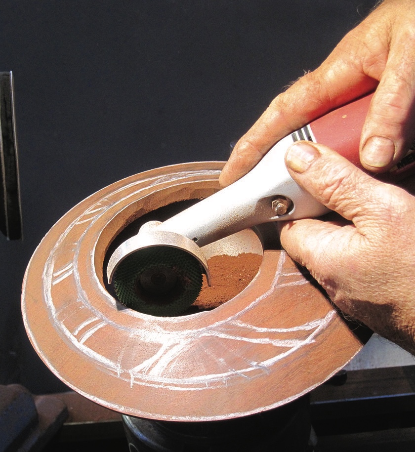 Hands using angle grinder on wooden bowl