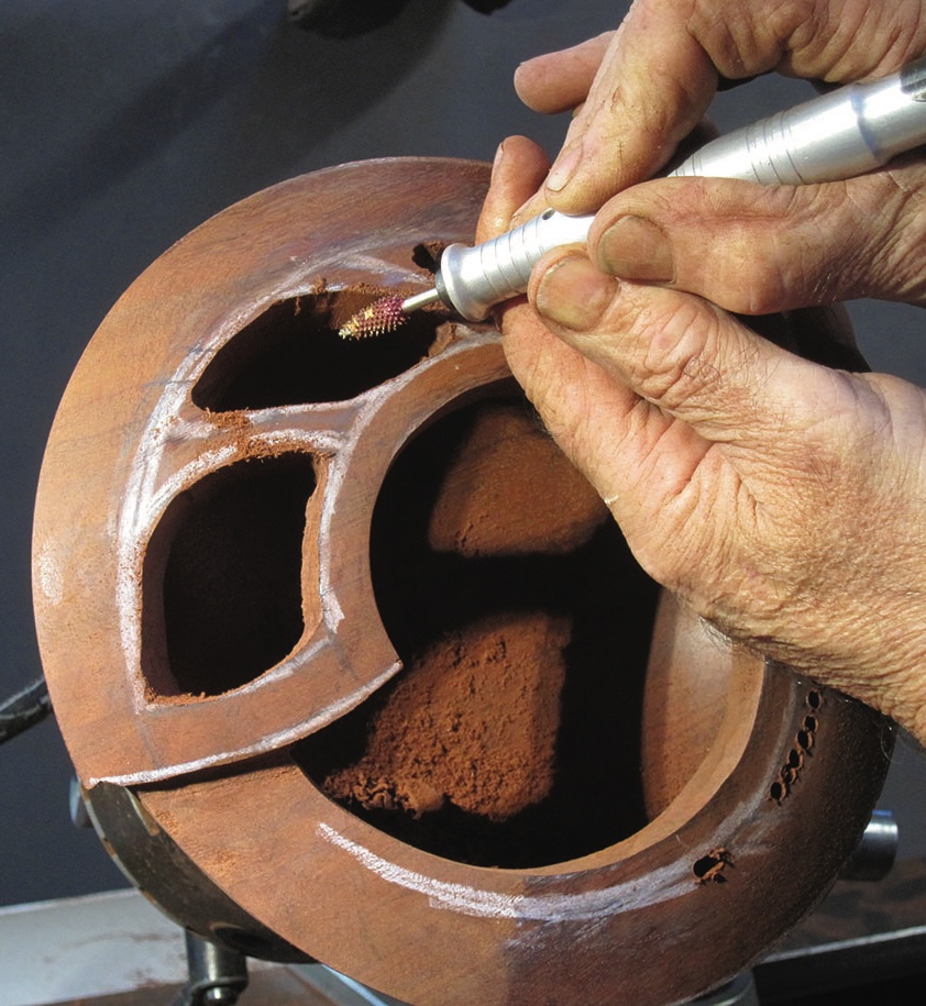 Hands carving intricate wooden bowl design