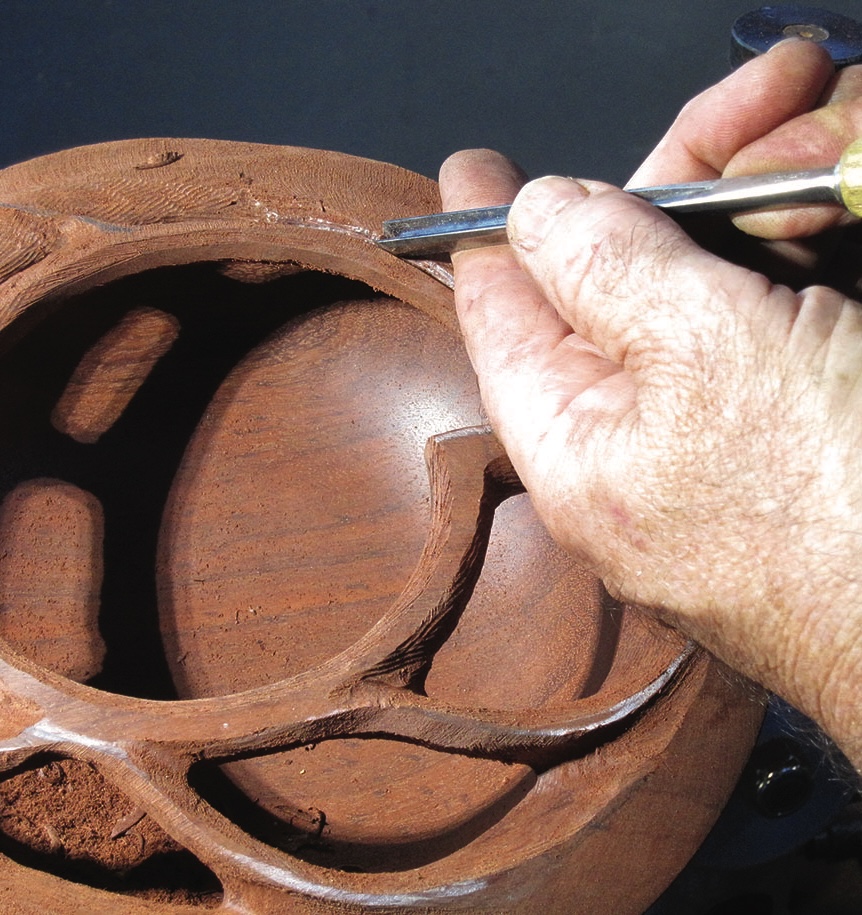 Hand carving intricate designs into wooden sculpture.