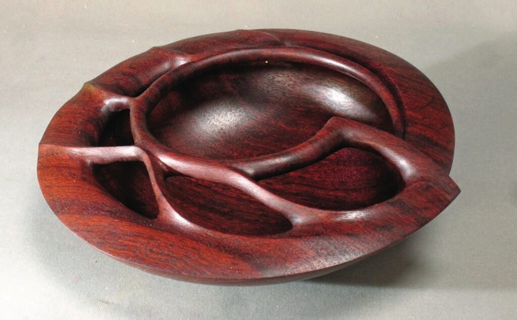 Intricate carved wooden bowl with abstract design.