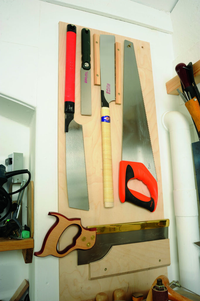 Assorted saws neatly hung on a workshop wall.