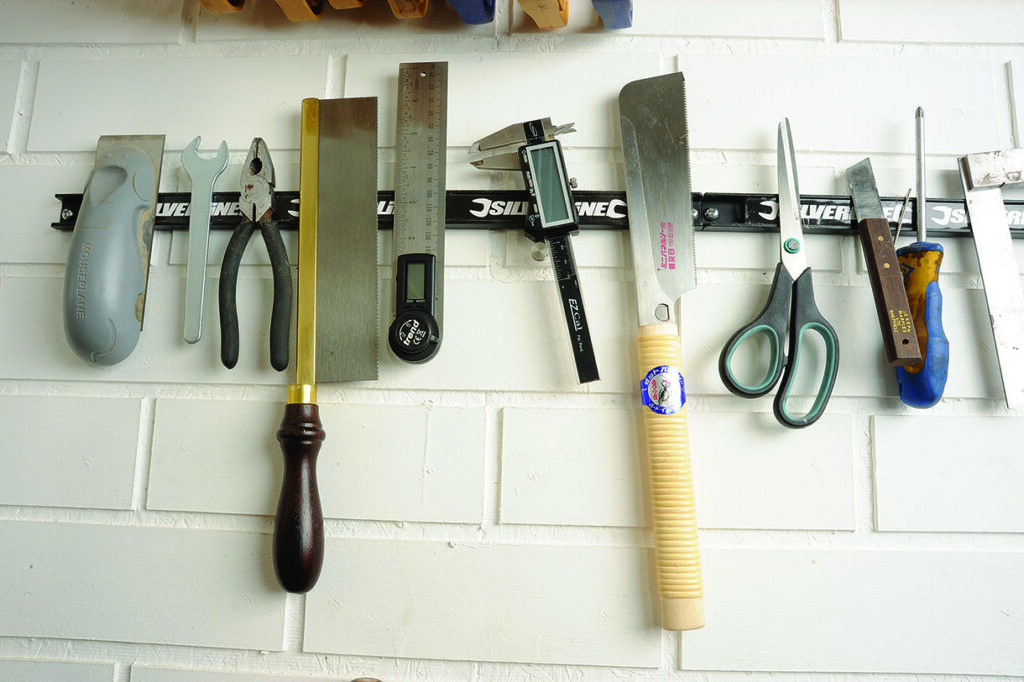 Various hand tools hanging on a wall rack.