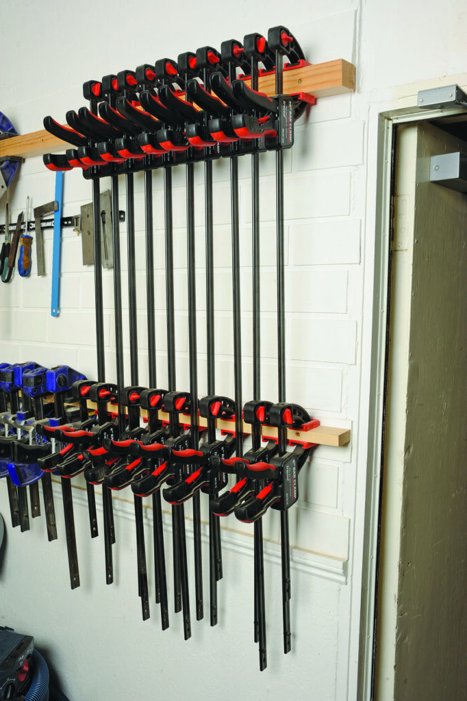 Wall-mounted clamps organised in a workshop.