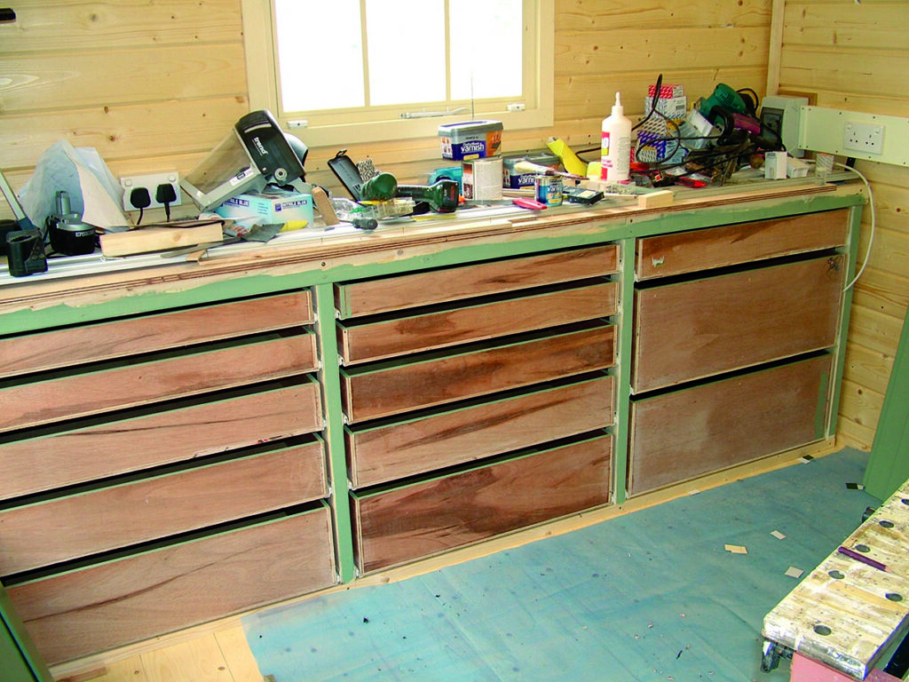 Wooden workshop drawers with tools and supplies.