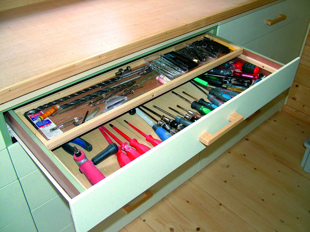 Open drawer with various hand tools inside.