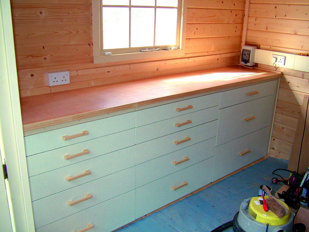 Wooden shed with workbench and drawers.