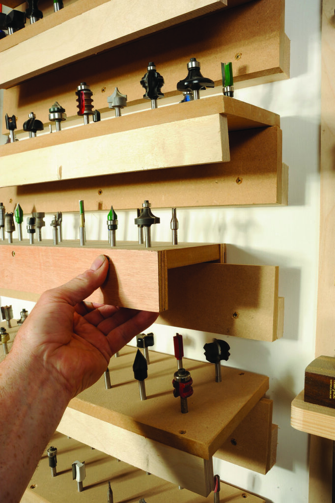 Woodworker selecting drill bit from storage rack.