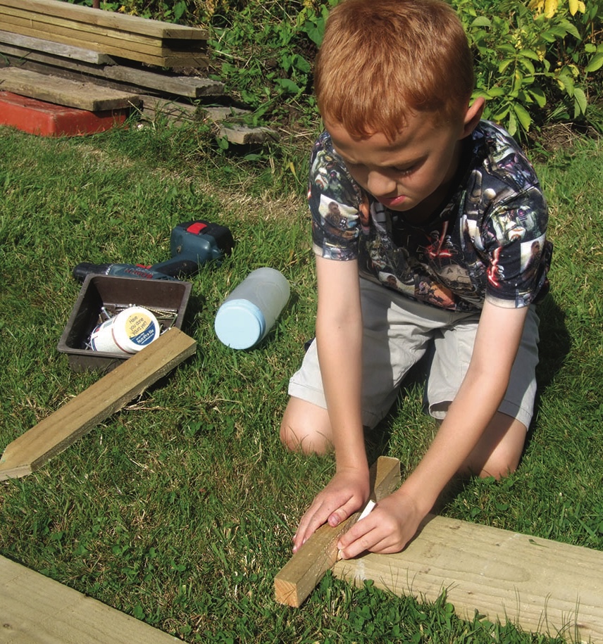 Boy measuring timber for a garden project