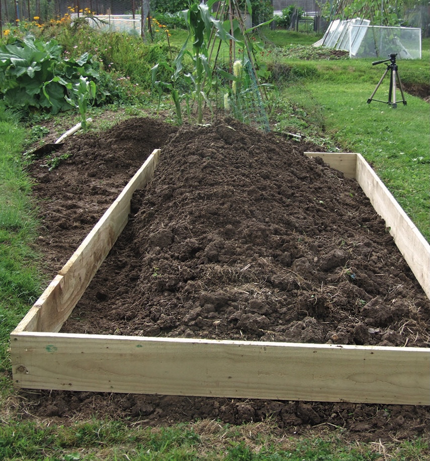 Wooden raised garden bed filled with freshly turned soil